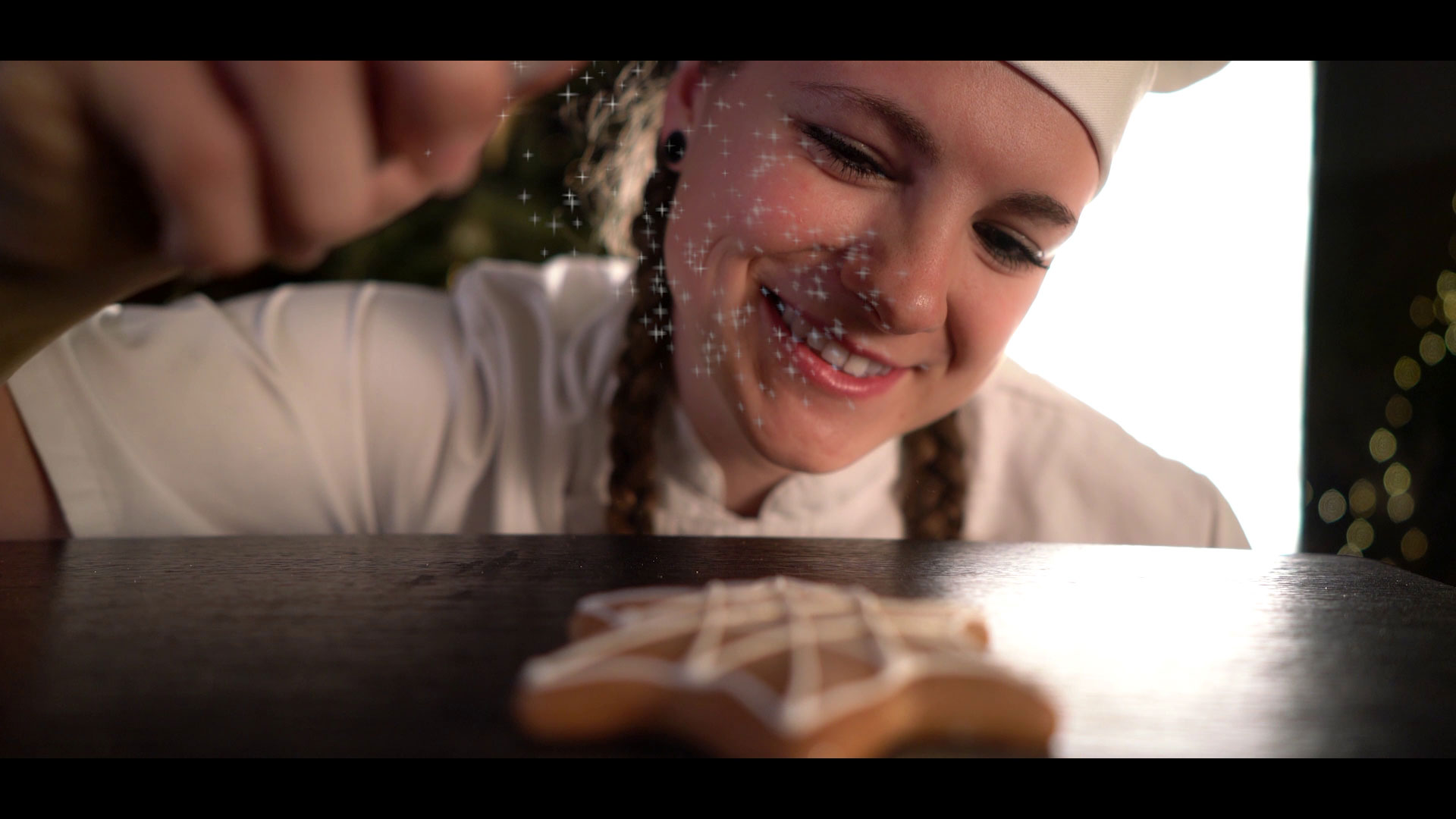 A baker sprinkles powder on a gingerbread